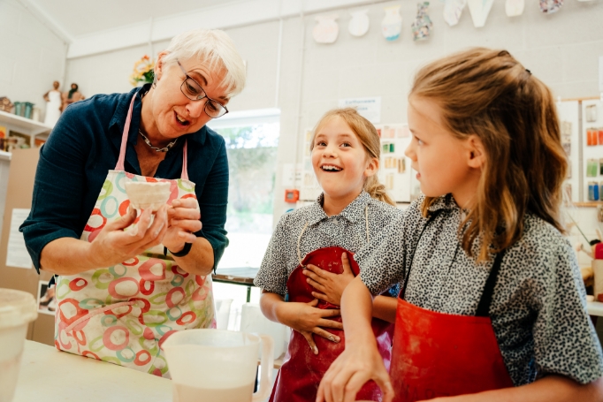 teacher demonstrating pottery technique to students