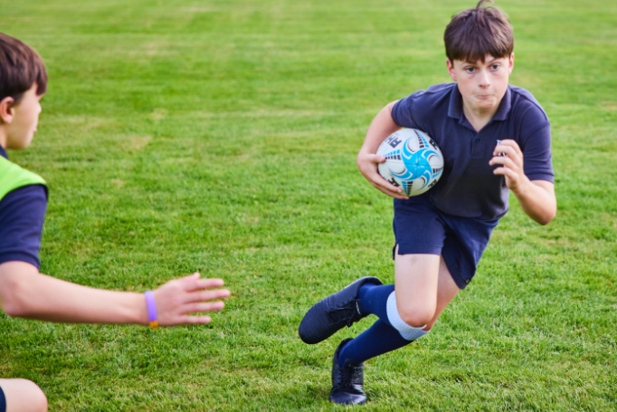 student running with rugby ball