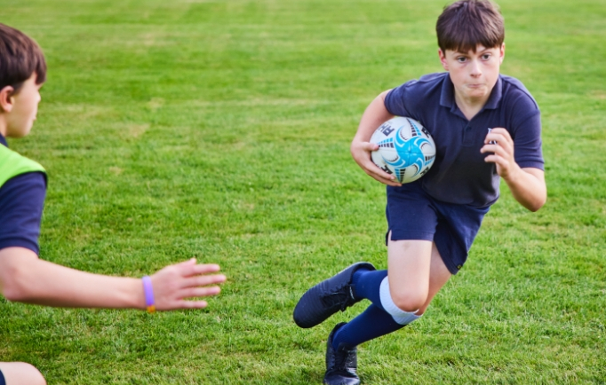 student running with rugby ball