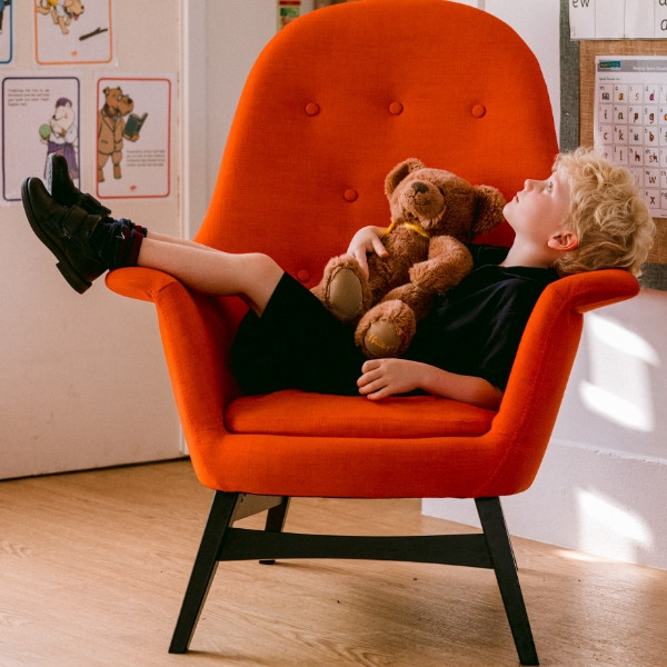 child with teddy bear in chair