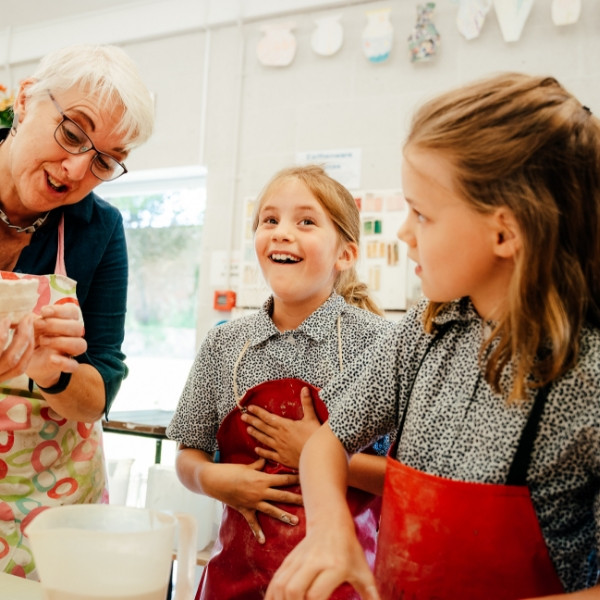 teacher showing excited students a clay model